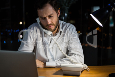 Businessman talking on phone while working in office