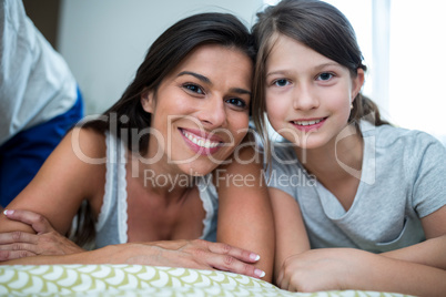 Portrait of mother and daughter lying in bedroom