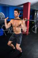 Man exercising with barbell in fitness studio