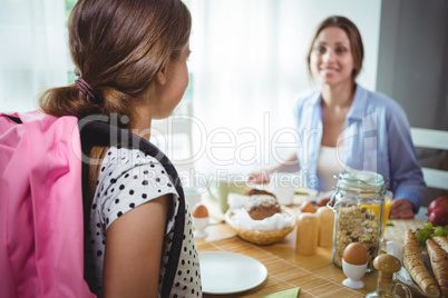 Mother interacting with her daughter while having breakfast