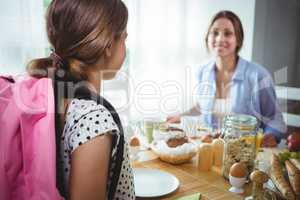 Mother interacting with her daughter while having breakfast