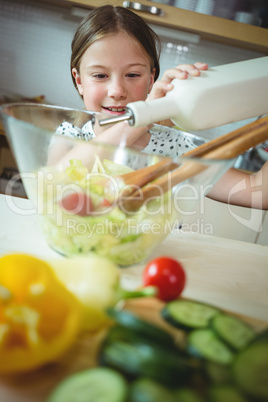 Girl preparing a bowl of salad in kitchen