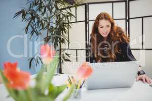 Happy businesswoman using laptop at creative office