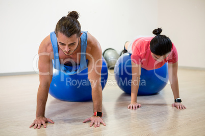 Men doing push-up on exercise ball