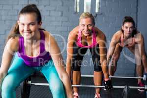 Smiling female athletes lifting barbells