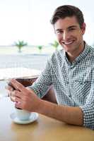 Smiling man using his mobile phone in coffee shop