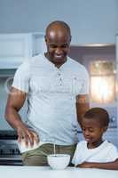 Son looking at father pouring milk in a bowl
