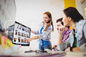 Businesswoman showing computer screen to coworkers