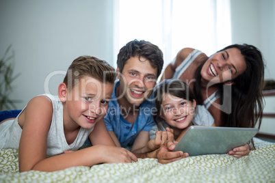 Happy family using digital tablet in bedroom at home