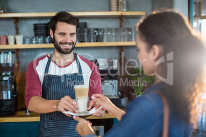 Waiter serving a cup of cold coffee to customer at counter