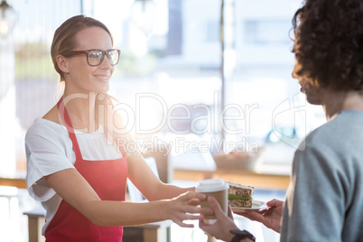 Waitress serving a coffee and sandwich to customer in cafÃ?Â©