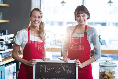 Smiling waitress standing with menu board in cafe