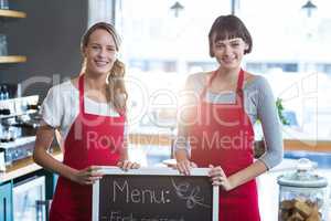 Smiling waitress standing with menu board in cafe