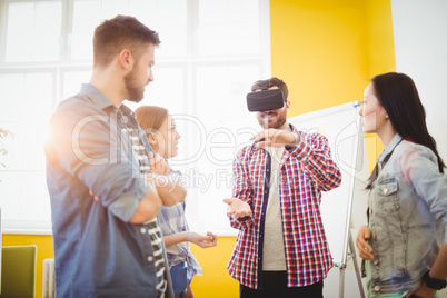 Colleagues looking at businessman wearing virtual reality headset