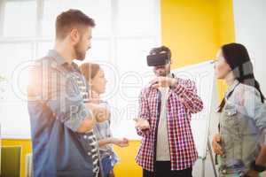Colleagues looking at businessman wearing virtual reality headset
