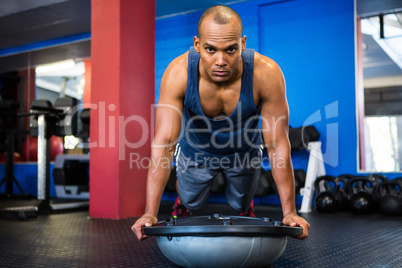 Portrait of serious male athlete with BOSU ball in gym