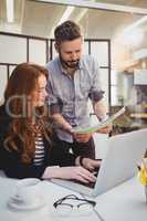 Businessman showing document to female colleague