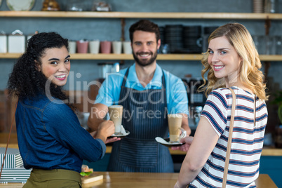 Waiter serving a cup of coffee to customer at counter