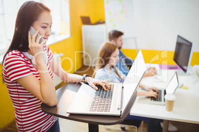 Businesswoman talking on phone while working in creative office