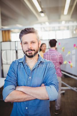 Portrait of confident businessman with arms crossed at creative office