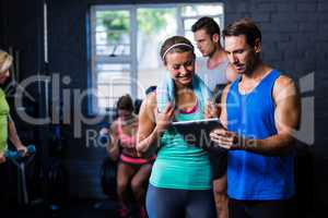 Man and woman looking in tablet computer at gym