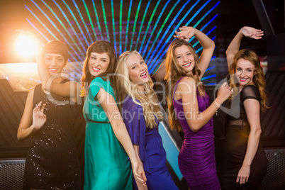 Group of smiling friends dancing on dance floor