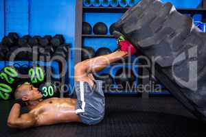 Side view of male athlete with tire in gym