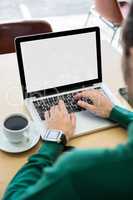 Man using laptop with coffee cup on table