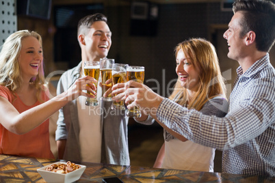 Friends toasting glasses of beer at bar counter