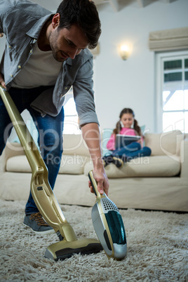 Man cleaning a carpet with a vacuum cleaner