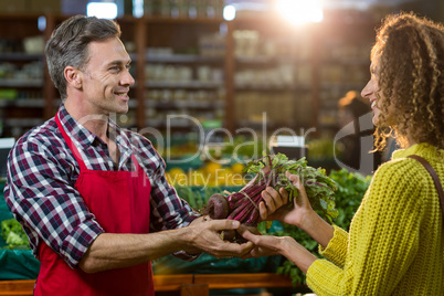 Smiling male staff assisting a woman with grocery shopping