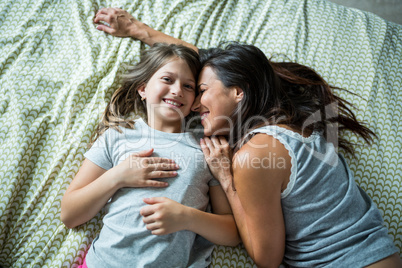 Mother and daughter playing on bed