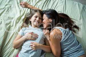 Mother and daughter playing on bed