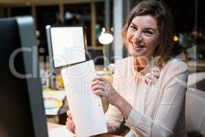 Portrait of businesswoman holding document at her desk