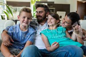 Happy family sitting with arm around on sofa