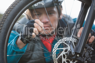 Male mountain biker examining front wheel of his bicycle