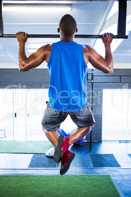 Male athlete doing chin-ups in fitness studio
