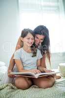 Mother and daughter reading book on bed