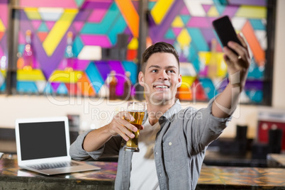 Young man taking a selfie while having a glass of beer Young man taking a selfie while having a glass of beer