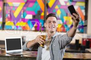 Young man taking a selfie while having a glass of beer