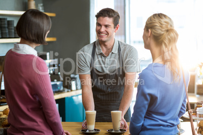 Waiter serving a cup of coffee to customer at counter