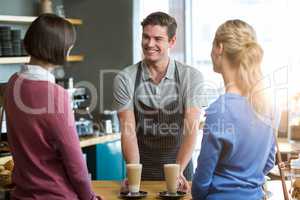 Waiter serving a cup of coffee to customer at counter