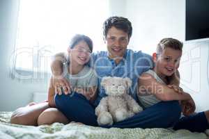 Portrait of father and kids sitting in bedroom