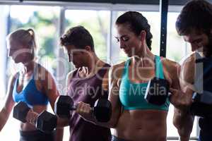 Young friends holding dumbbells in gym