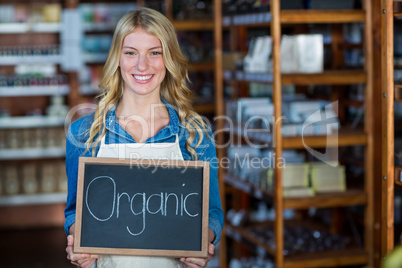 Portrait of smiling female staff holding a organic sign board