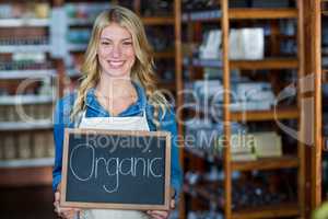 Portrait of smiling female staff holding a organic sign board