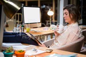 Businesswoman using digital tablet and holding coffee cup at her desk