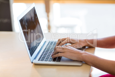 Waitress sitting at table and using laptop