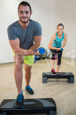 Portrait of man and woman doing aerobic exercise with dumbbell