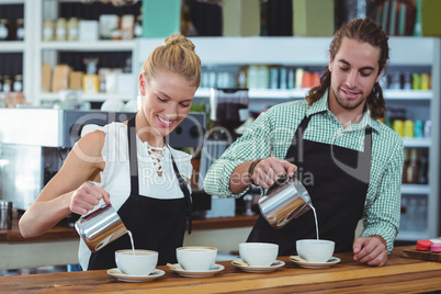 Smiling waiter and waitress making cup of coffee at counter